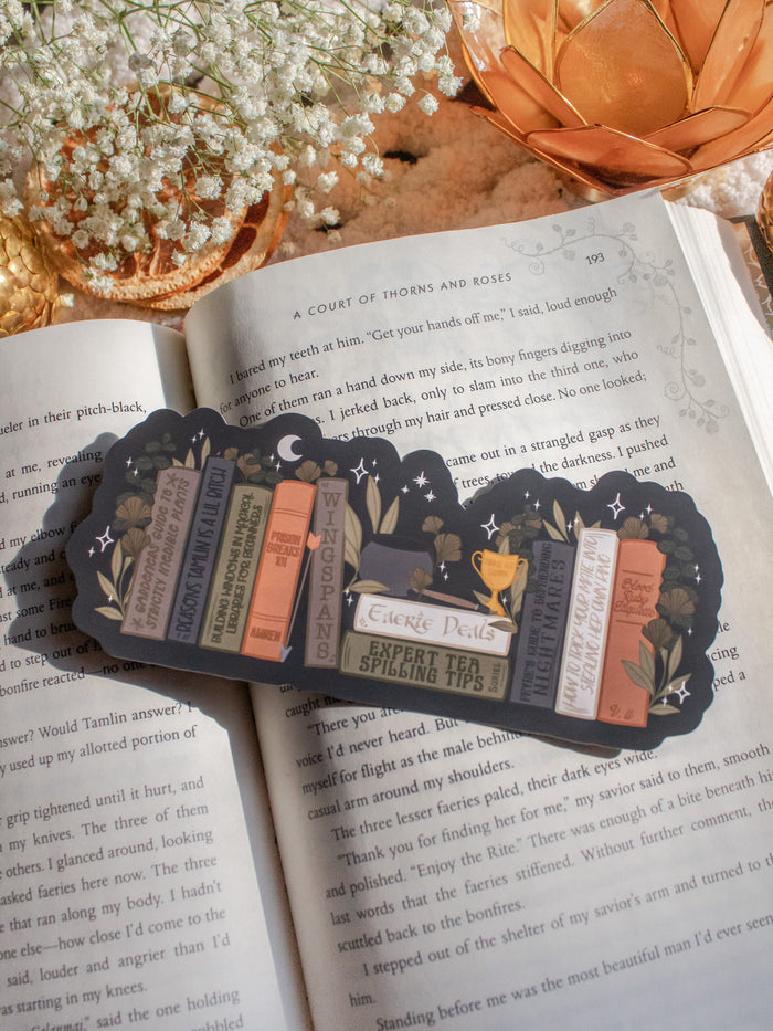 ACOTAR Funny Feyre Bookshelf Bookmark from A Court of Thorns and Roses by Sarah J Maas. A Bookshelf in earth tones like deep greens, browns and charcoal with a cauldron and a "snowball fight champion" trophy with book titles like "Reasons Tamlin is a lil bitch", "A Gardeners guide to strictly inedible plants", "Prison Breaks 101" and more.