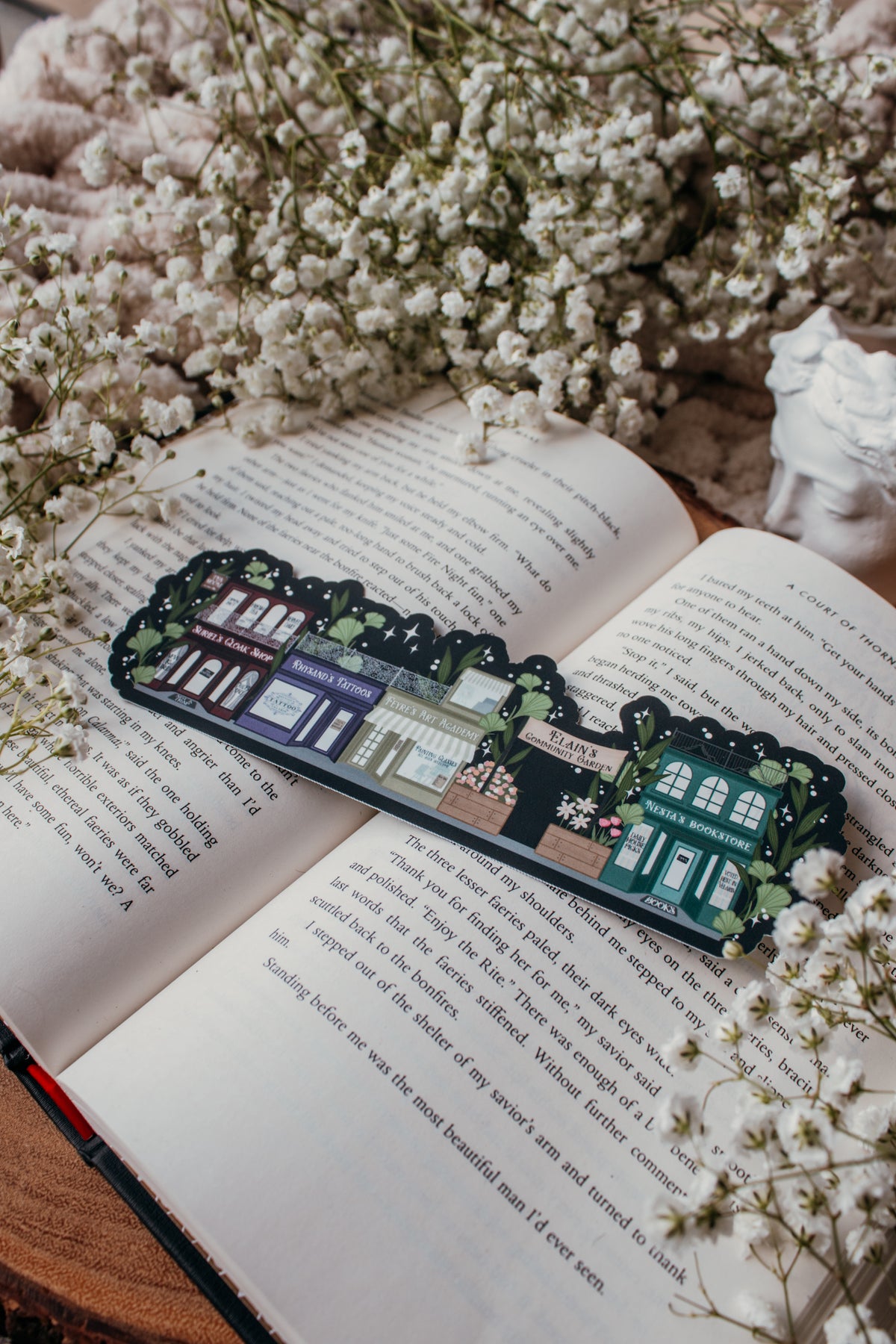 ACOTAR A Walk in Velaris Bookmark is an imagined velaris scene with fake shops like Nesta's bookstore, Elain's community garden (with only flowers in it), Feyre's Art Academy, Rhysand's Tattoo Parlor, and the Suriels Cloak Shop/ Tea Room. Inspired from A Court of Mist and Fury by Sarah J. Maas.