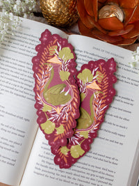 This fantasy autumnal fall sleeping dragon elixir bookmark features a little green dragon curled up in a potion bottle with their tale sticking out the top. Surrounded by orange, green, and light pink foliage with little stars and magic bubbles floating around. On a maroon background