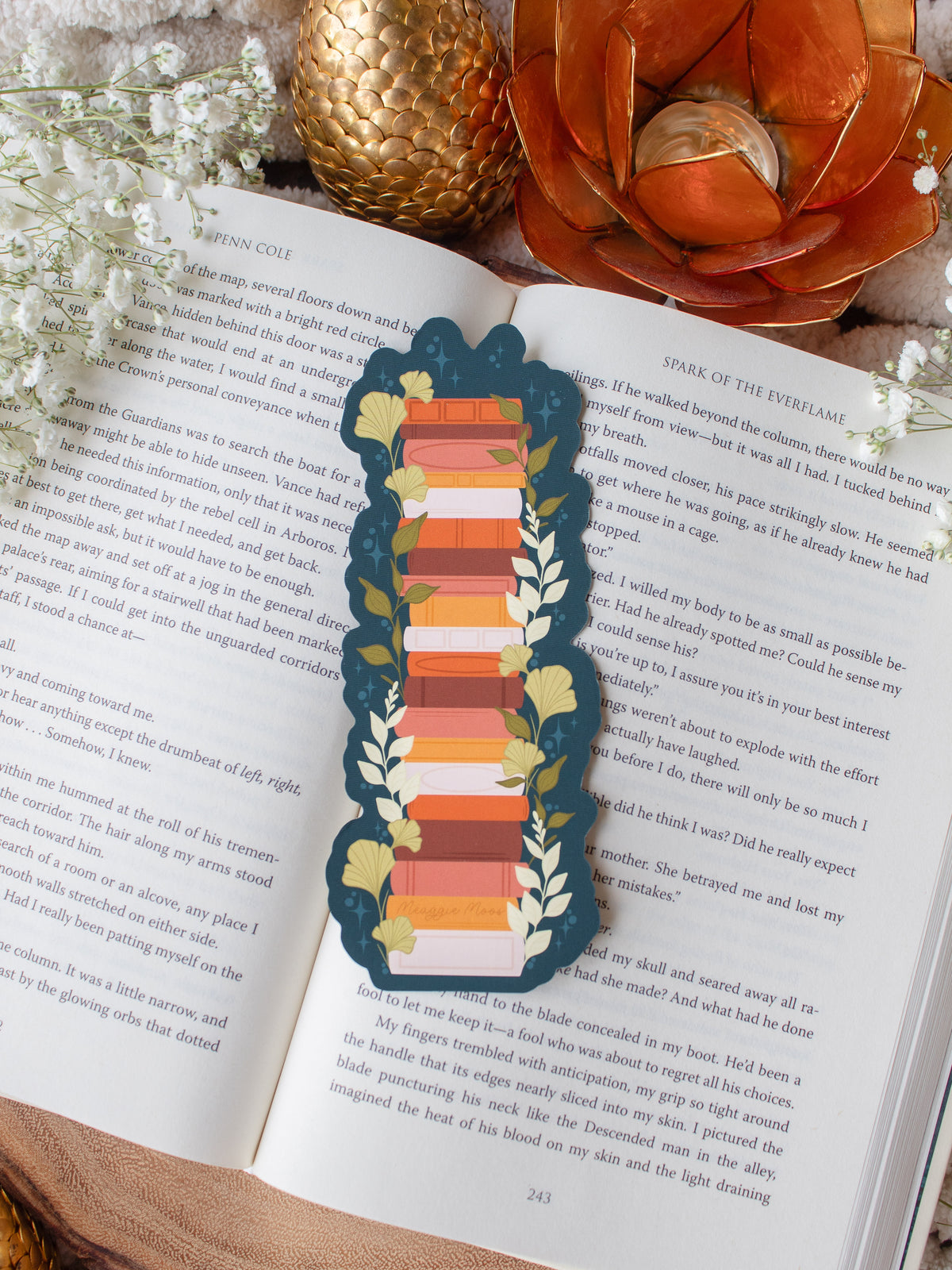 This moody toned fall autumn bookstack bookmark is a bookstack in warm tones, like mustard yellow, cream, coral, and burnt orange on a deep teal background.