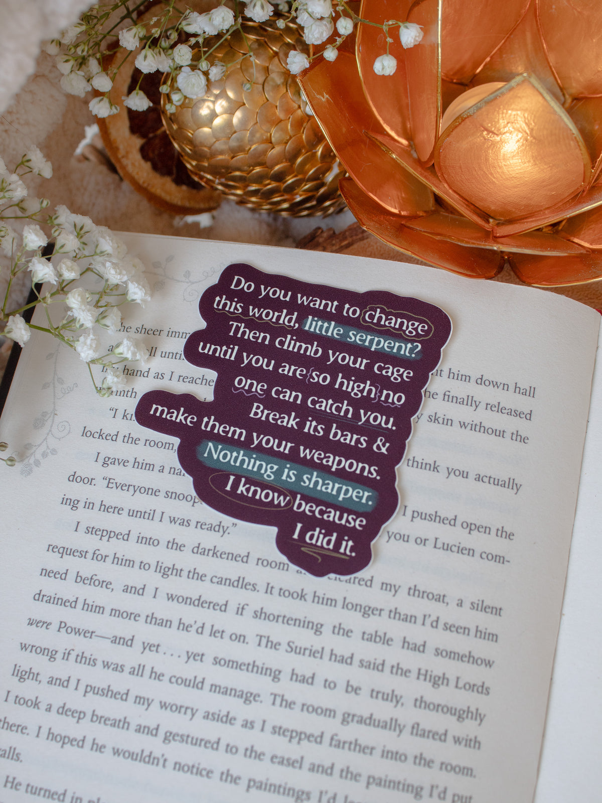 This officially licensed Serpent and the Wings of Night Sticker from the Crowns of Nyaxia Series by Carissa Broadbent features type-writer style cream text on a deep maroon background with teal, light green, and purple/pink annotations style accents.