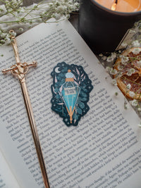 Spark Of The Everflame Henri's Tears Potion Sticker from the Kindred's Curse Saga by Penn Cole. This officially licensed sticker has a dark teal background, with a diamond shaped potion, light teal contents, surrounded by various shades of teal and pink foliage, stars, a crescent moon, and lil magical bubbles.