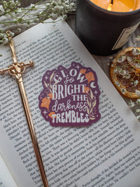 Maroon Sticker with the text "low So Bright The Darkness Trembles" from Spark of the Everflame by Penn Cole from the Kindred's Curse Saga. The text on this officially licensed sticker is surrounded by orange and tan foliage, stars, and magical looking bubbles.