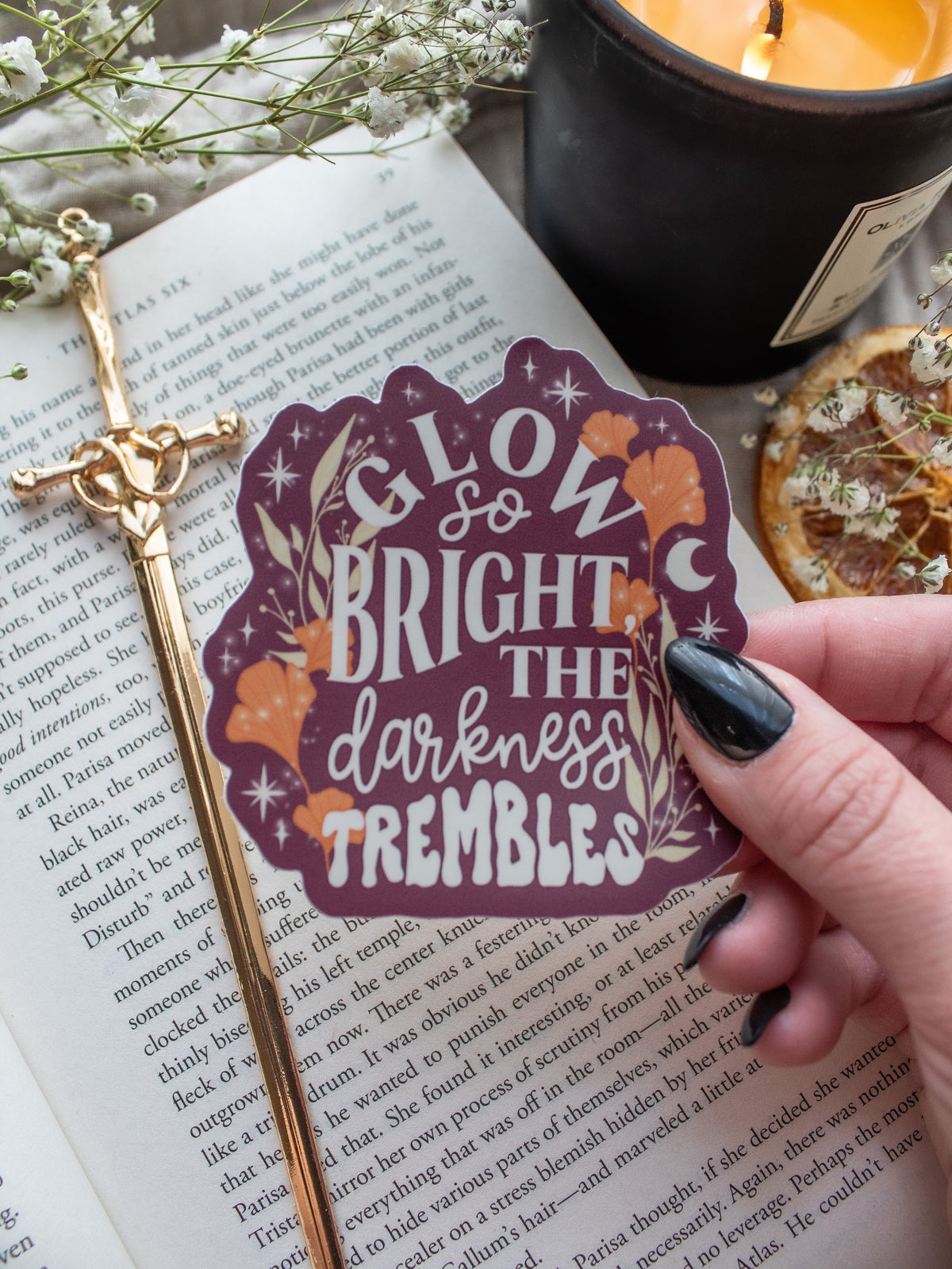 Maroon Sticker with the text "low So Bright The Darkness Trembles" from Spark of the Everflame by Penn Cole from the Kindred's Curse Saga. The text on this officially licensed sticker is surrounded by orange and tan foliage, stars, and magical looking bubbles.