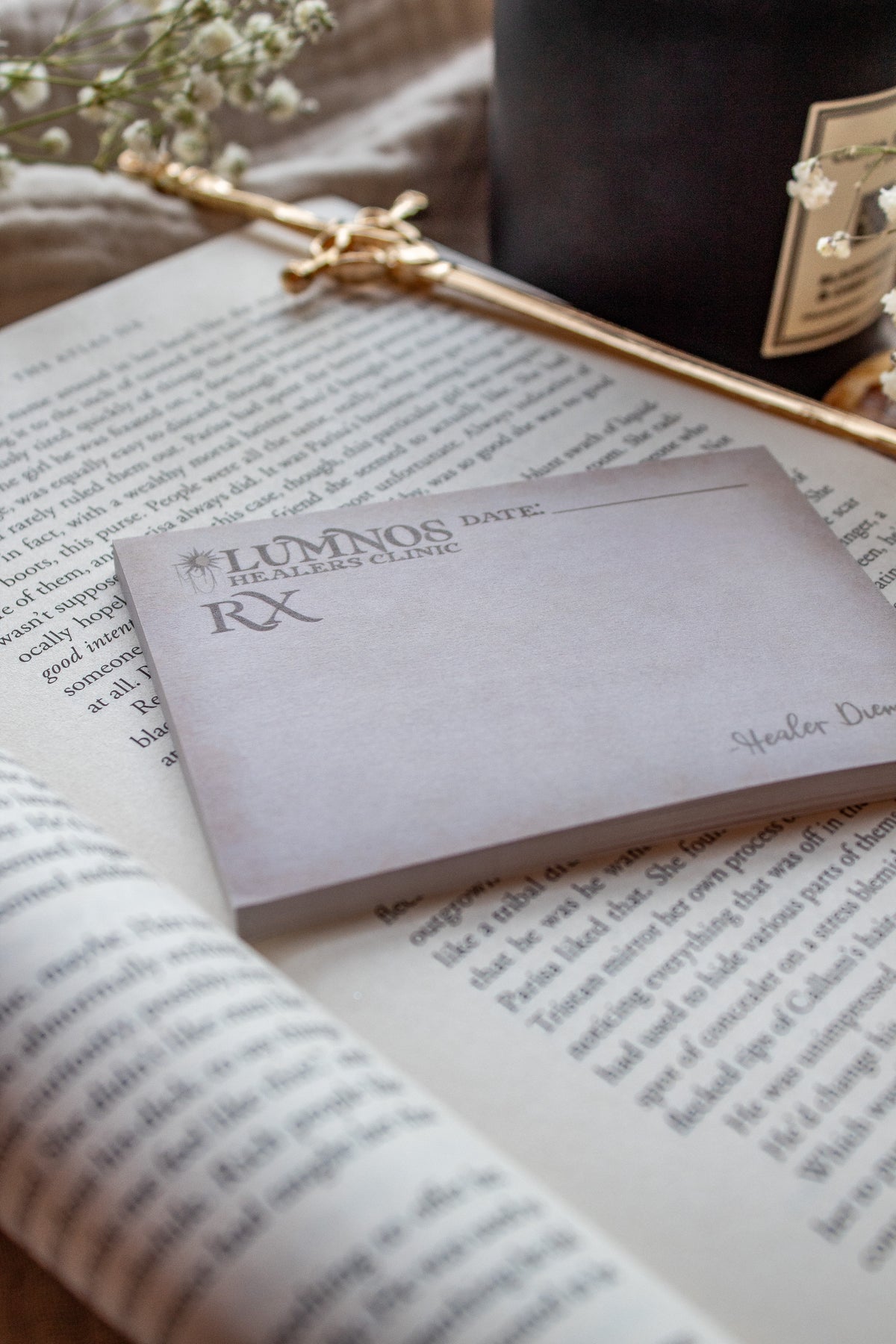 Spark of The Everflame Lumnos Healers Clinic RX Notepad. Inspired by the Kindreds Curse Saga by Penn Cole. This licensed 3"x4" post-it notepad looks like aged parchment, and has "Lumnos Healers Clinic - RX"  and a date line along the top then its signed off by Diem on the bottom corner.
