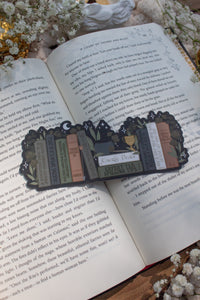 ACOTAR Funny Feyre Bookshelf Bookmark from A Court of Thorns and Roses by Sarah J Maas. A Bookshelf in earth tones like deep greens, browns and charcoal with a cauldron and a "snowball fight champion" trophy with book titles like "Reasons Tamlin is a lil bitch", "A Gardeners guide to strictly inedible plants", "Prison Breaks 101" and more.