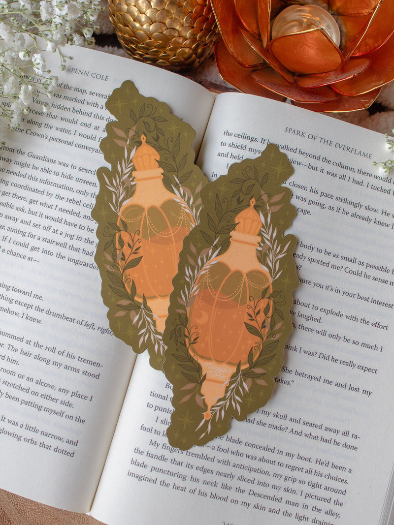 This fall autumn fantasy pumpkin spice potion bookmark features a pumpkin shaped potion bottle, in orange and yellow/gold on a deep green background with curling foliage, stars and magic bubbles surrounding it. 