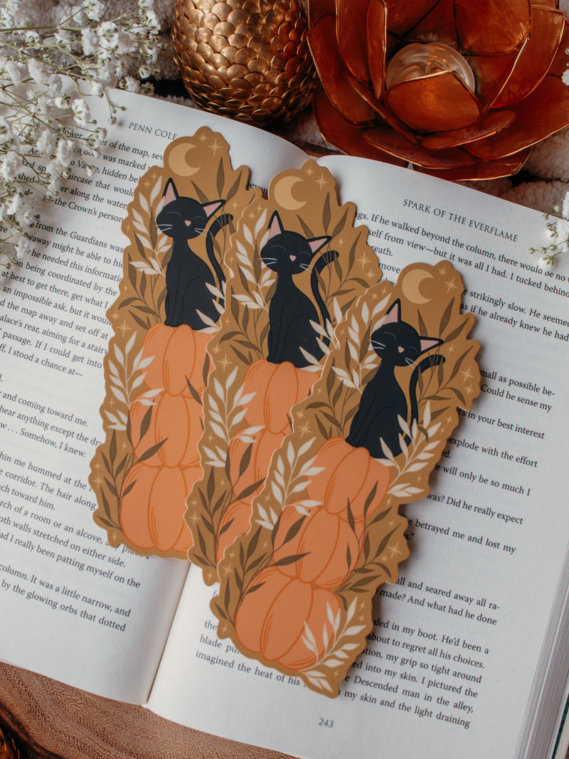 This adorable Fall / Autumn Pumpkin stack kitty cat bookmark has a deep chartreuse background, with a stack of 3 pumpkins and a little black kitty cat sitting on top. Surrounded by foliage and little stars. 