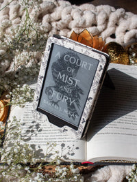 Ivory Swords Fantasy Reader Dragon Kindle Case. It has an ivory background with deep charcoal dragons, swords, crowns, and foliage all over it. This is a full cover kindle case with a leatherette outside, a kick-stand, card-slot, and hand-strap. 