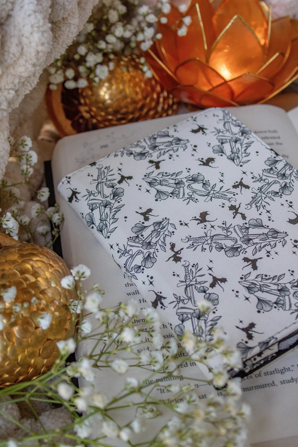 Ivory Swords Fantasy Reader Dragon Kindle Case. It has an ivory background with deep charcoal dragons, swords, crowns, and foliage all over it. This is a full cover kindle case with a leatherette outside, a kick-stand, card-slot, and hand-strap. 