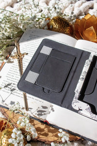 Ivory Swords Fantasy Reader Dragon Kindle Case. It has an ivory background with deep charcoal dragons, swords, crowns, and foliage all over it. This is a full cover kindle case with a leatherette outside, a kick-stand, card-slot, and hand-strap. 