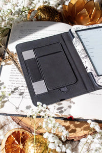 Ivory Swords Fantasy Reader Dragon Kindle Case. It has an ivory background with deep charcoal dragons, swords, crowns, and foliage all over it. This is a full cover kindle case with a leatherette outside, a kick-stand, card-slot, and hand-strap. 