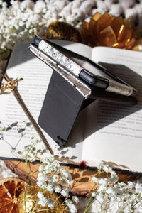 Ivory Swords Fantasy Reader Dragon Kindle Case. It has an ivory background with deep charcoal dragons, swords, crowns, and foliage all over it. This is a full cover kindle case with a leatherette outside, a kick-stand, card-slot, and hand-strap. 