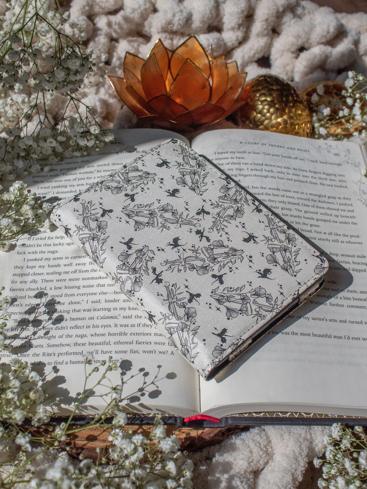 Ivory Swords Fantasy Reader Dragon Kindle Case. It has an ivory background with deep charcoal dragons, swords, crowns, and foliage all over it. This is a full cover kindle case with a leatherette outside, a kick-stand, card-slot, and hand-strap. 