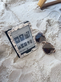 Ivory Swords Fantasy Reader Dragon Kindle Case. It has an ivory background with deep charcoal dragons, swords, crowns, and foliage all over it. This is a full cover kindle case with a leatherette outside, a kick-stand, card-slot, and hand-strap. 