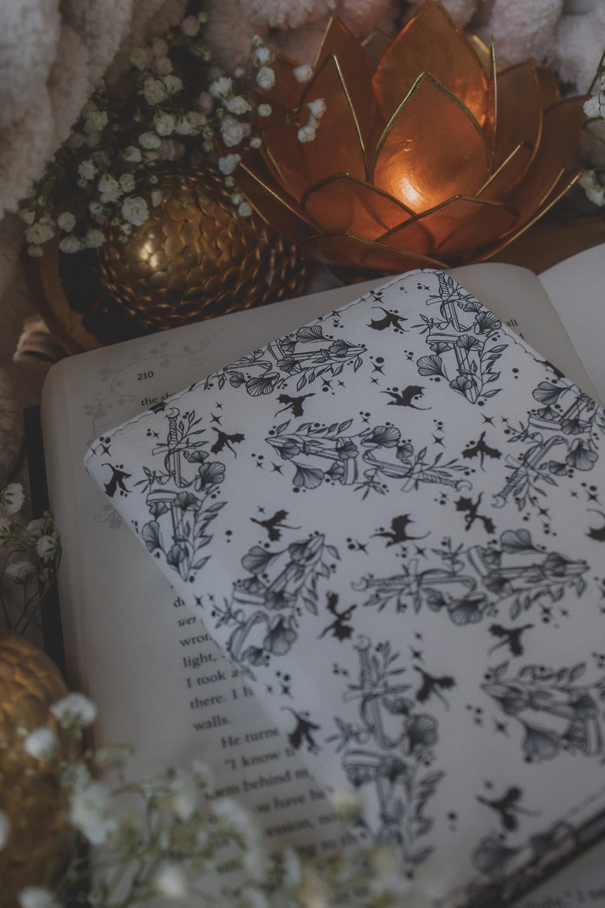 Ivory Swords Fantasy Reader Dragon Kindle Case. It has an ivory background with deep charcoal dragons, swords, crowns, and foliage all over it. This is a full cover kindle case with a leatherette outside, a kick-stand, card-slot, and hand-strap. 