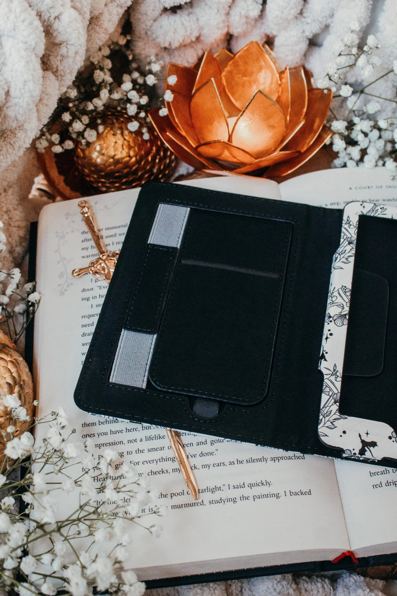 Ivory Swords Fantasy Reader Dragon Kindle Case. It has an ivory background with deep charcoal dragons, swords, crowns, and foliage all over it. This is a full cover kindle case with a leatherette outside, a kick-stand, card-slot, and hand-strap. 