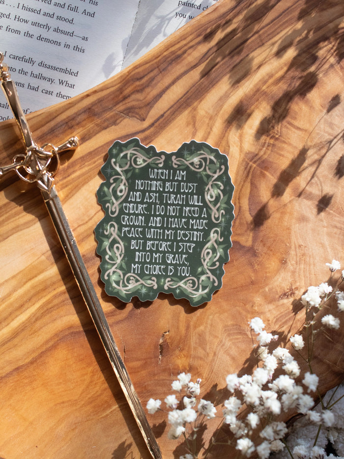 Shield of Sparrow bookish waterproof vinyl sticker inspired by Devney Perry series. This sticker is dark green, rectangular in shape with the "My Choice Is You" on it in an art nouveau font, and wood vines drawn around it in a Nordic Viking-style where they are woven together, foliage is intertwined with the wood vines and little magical looking bubbles surround them both. 

The sticker is sitting on an olive wood cutting board, on top of an open book, with little white flowers surrounding it.