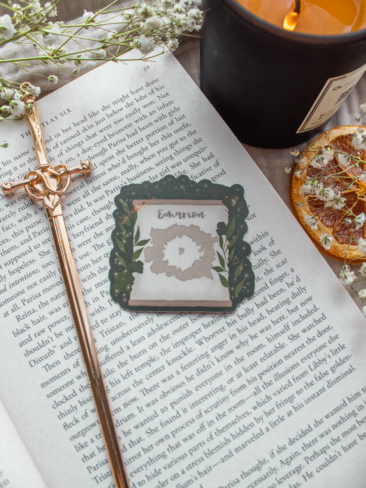 Spark of The Everflame Emarion Map Sticker. From The Kindred's Curse Saga by Penn Cole. This Licensed sticker has a dark green background with a banner showing a map of Emarion on it, with Diem's Lumnos crown hanging off the corner. 