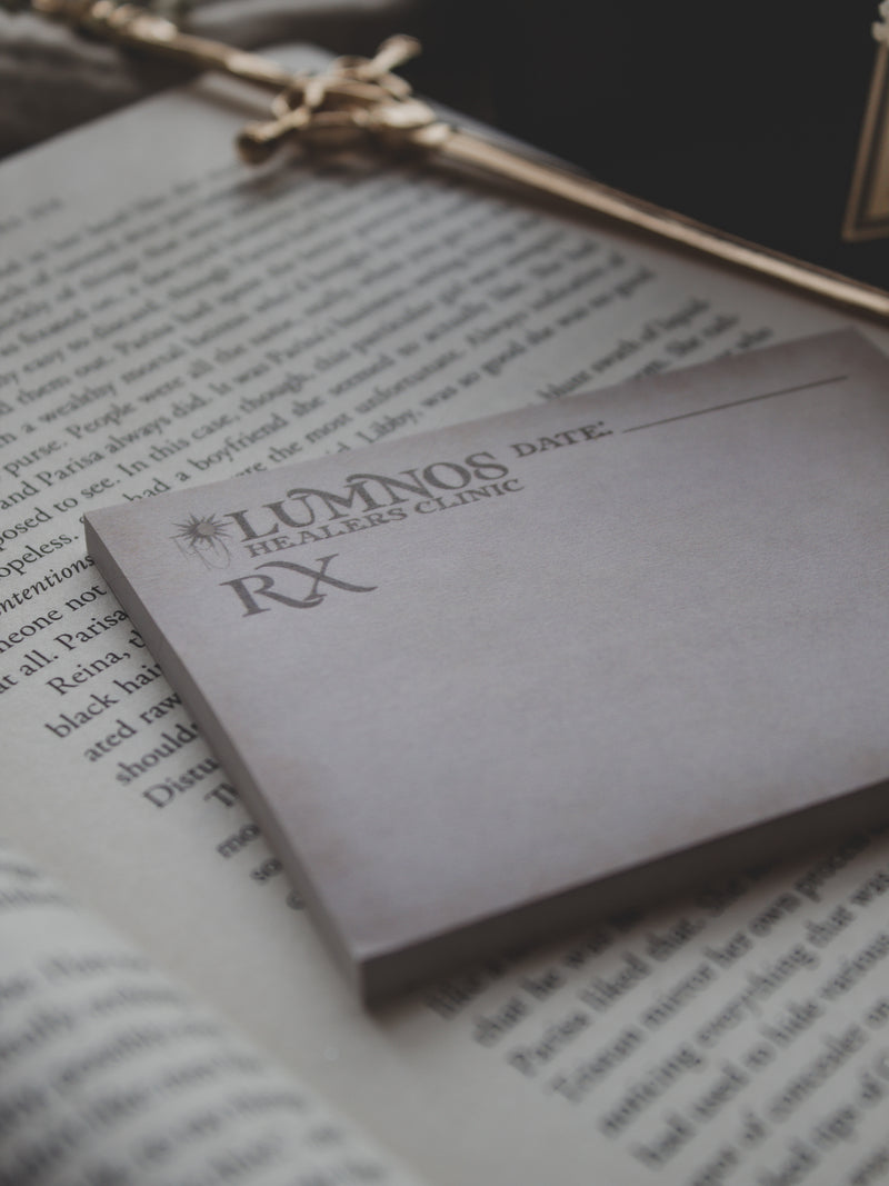 Spark of The Everflame Lumnos Healers Clinic RX Notepad. Inspired by the Kindreds Curse Saga by Penn Cole. This licensed 3"x4" post-it notepad looks like aged parchment, and has "Lumnos Healers Clinic - RX"  and a date line along the top then its signed off by Diem on the bottom corner.  