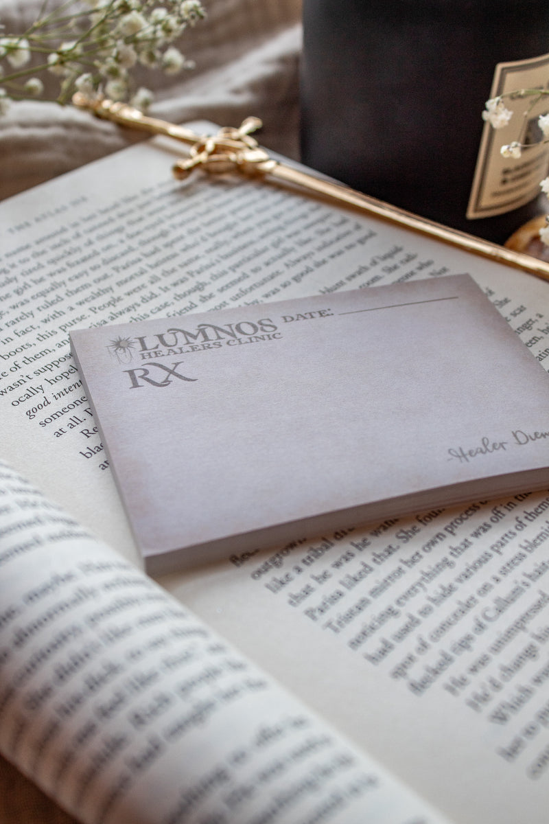 Spark of The Everflame Lumnos Healers Clinic RX Notepad. Inspired by the Kindreds Curse Saga by Penn Cole. This licensed 3"x4" post-it notepad looks like aged parchment, and has "Lumnos Healers Clinic - RX"  and a date line along the top then its signed off by Diem on the bottom corner.  