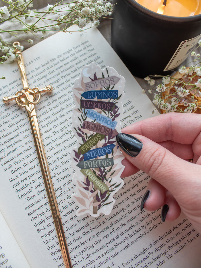 Spark of the Everflame Emarion Realms Location Sign Sticker, from the Kindred's Curse Saga by Penn Cole. This officially licensed sticker shows a location sign with different realms on wooden arrows pointing in different directions. A solid sticker with a beige background.  