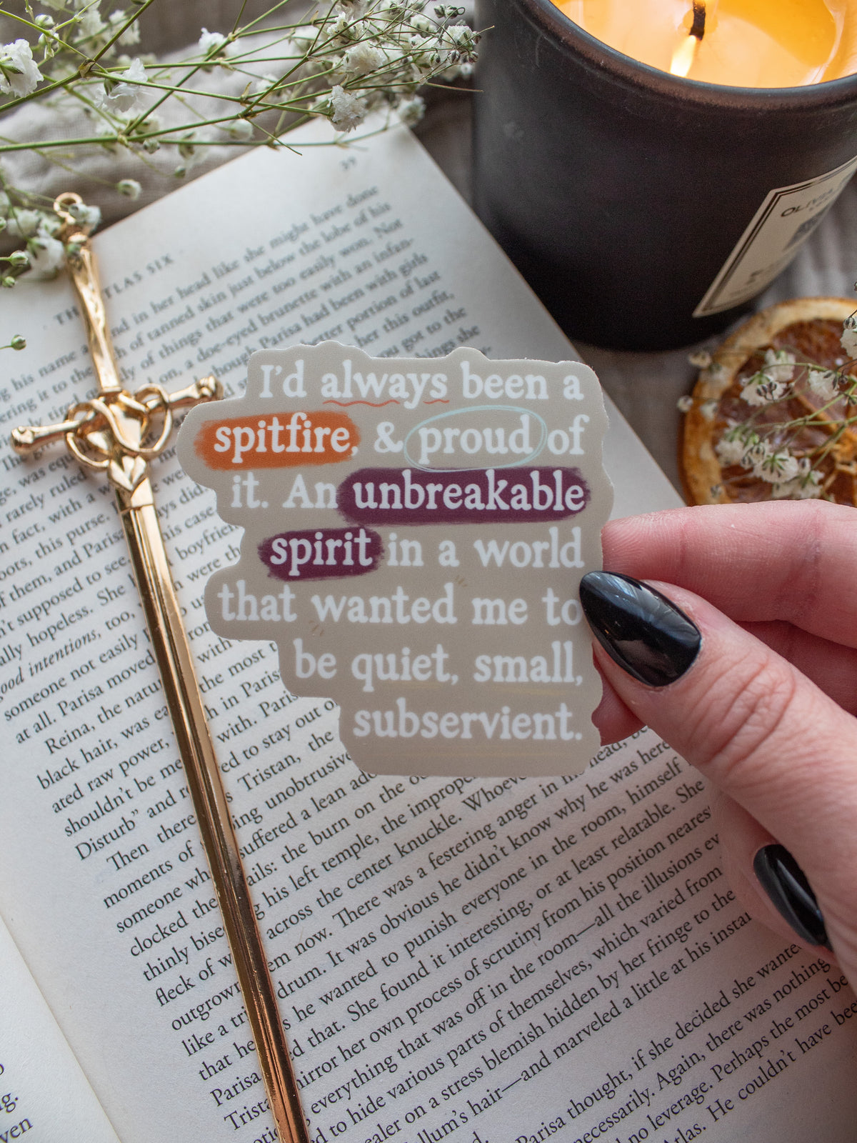 Spark of The Everflame "I'd always been a spitfire, and proud of it. An unbreakable spirit in a world that wanted me to be quiet, small, subservient." quote. Inspired from the novel from The Kindred's Curse Saga by Penn Cole, this officially licensed sticker has a camel background, with white type-writer style text and annotation like highlighting, circling, and underlining. 