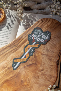 This Sucker for True Crime Die-Cut Bookmark is for all my mystery loving book babes who love to delve into a good cold case file. 

It is a dark grey heart shaped sucker with blood dripping off of it, wrapped in crime scene tape and surrounded by stars on a darker grey background.


The bookmark is sitting on an olive wood cutting board, on an open book, with little white flowers surrounding it.