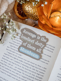 This When the Moon Hatched Quote Sticker from the Moonfall series by Sarah A Parker is a dark taupe with light blue and green annotation style accents around the quote "Revenge is the loneliest deity of them all, Moonbeam"