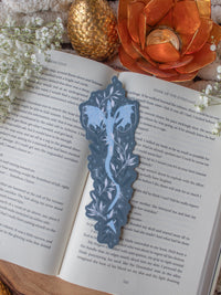 This When The Moon Hatched Moonplume Dragon Bookmark is from the Moonfall Series by Sarah A Parker. A light blue dragon is on a dust slate blue background with little magic bubbles