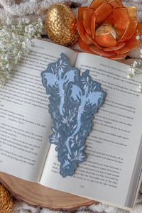 This When The Moon Hatched Moonplume Dragon Bookmark is from the Moonfall Series by Sarah A Parker. A light blue dragon is on a dust slate blue background with little magic bubbles