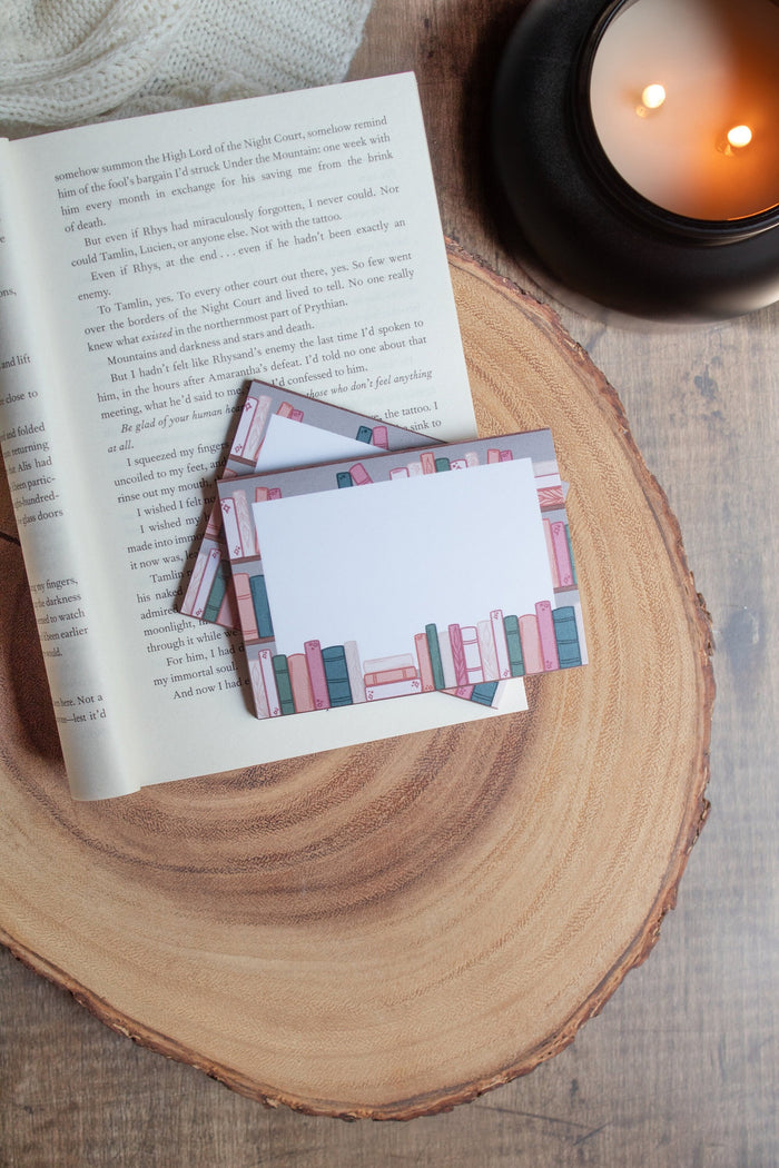 These bookshelf post-it notepads show a bookcase with a white box over them, with some books peeking over. 