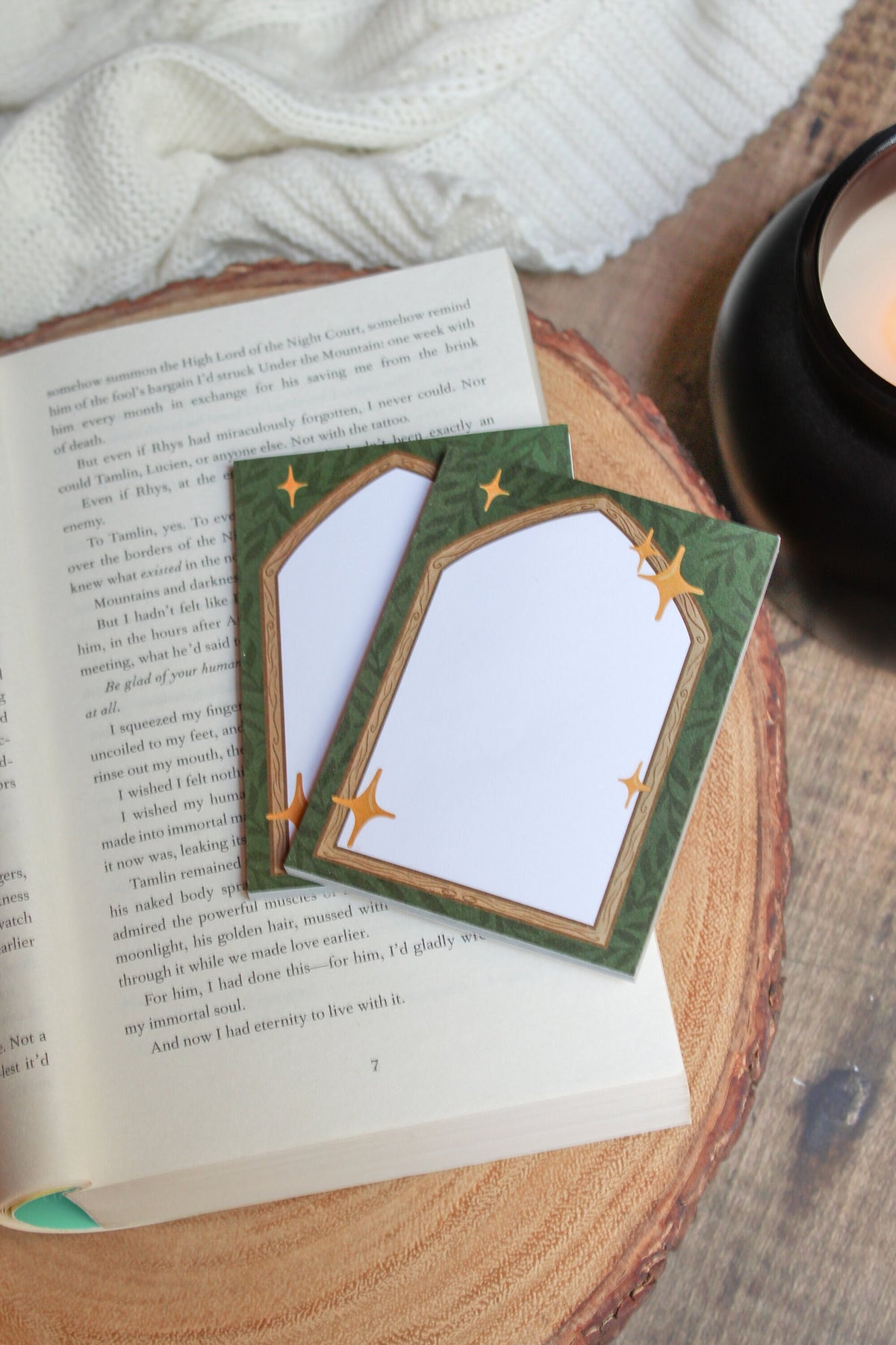 These Fantasy Bookish Archway Post-It Notepads have a dark green background with lil leaves on it. In front their is a wooden archway that comes to a point at the top. The center of the archway is solid write for the writing area. 
