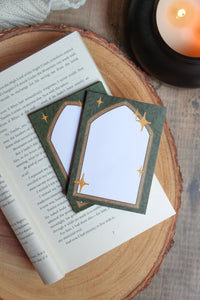 These Fantasy Bookish Archway Post-It Notepads have a dark green background with lil leaves on it. In front their is a wooden archway that comes to a point at the top. The center of the archway is solid write for the writing area. 