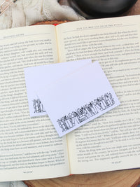 These bookish magical forest bookshelf post-it notepads are perfect to jot down all your bookish thoughts and ideas. They are 3"x4", have a white background with a black bookshelf along the bottom. The bookshelf have foliage peeking out from behind them. 