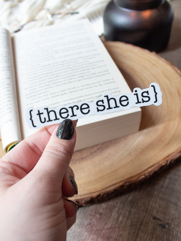 This There She Is sticker from The Serpent and The Wings of Night from the Crowns of Nyaxia Series by Carissa Broadbent is officially licensed. It features the text {there she is} in black on a solid white background