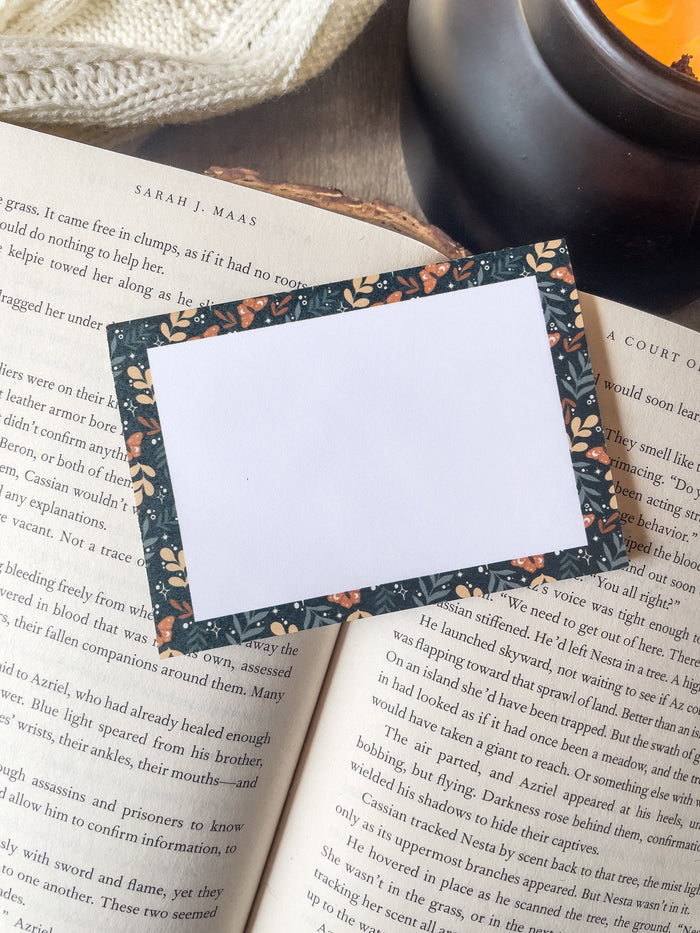 These floral faerie garden post-it notepads have a teal background with yellow and light sage green foliage and little orange celestial butterflies on them. Design is only around the border.